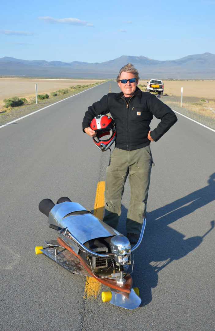 Picture of Bob Maddox standing on asphalt road near his Reaper 3 Pulsejet invention